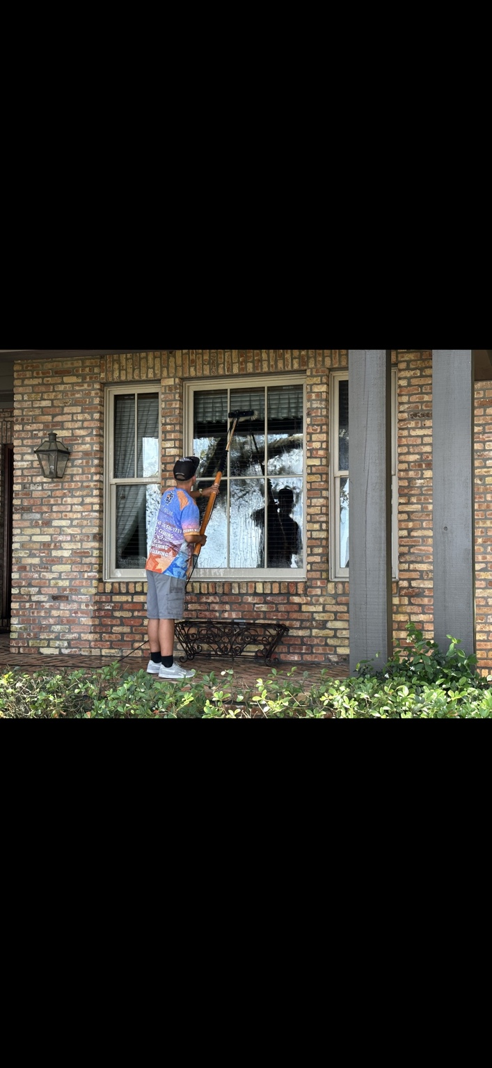 Optimum technician cleaning residential windows with a purified-water pole